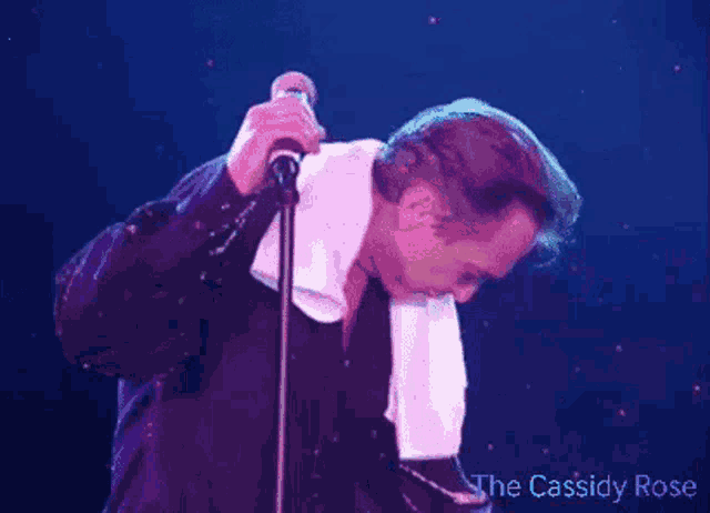 a man singing into a microphone with a towel around his neck and the words " the cassidy rose " on the bottom