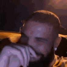 a close up of a man with a beard covering his face with his hands .