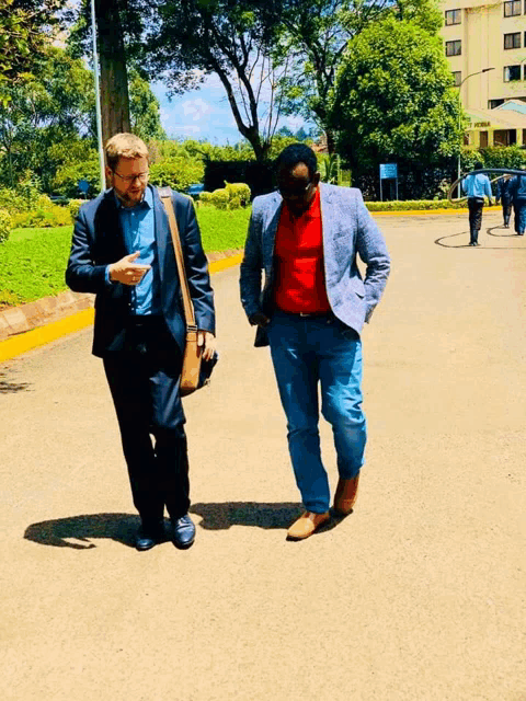 a man in a suit and a man in a red shirt are walking down the street