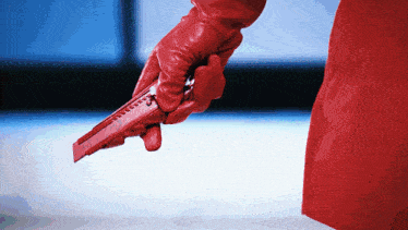 a person wearing a red glove is holding a red knife