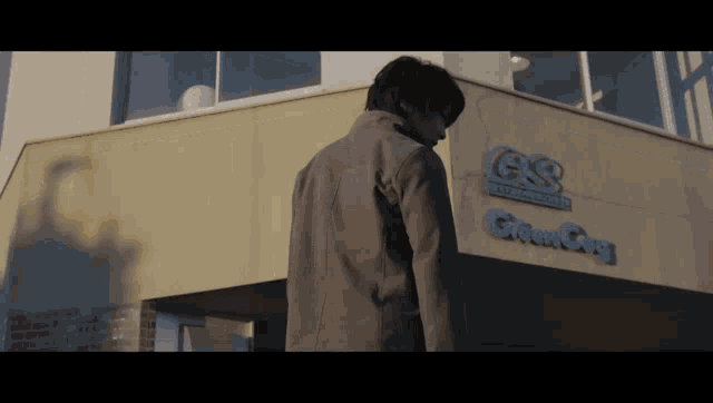 a man in a suit stands in front of a building that says g & s