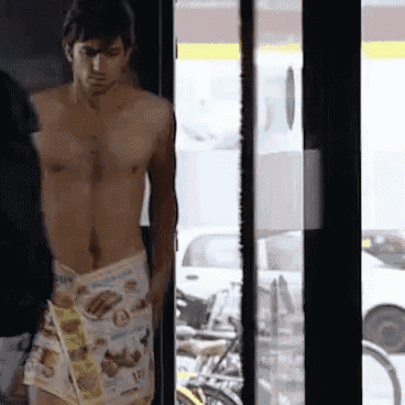 a shirtless man is standing in front of a glass door with a newspaper wrapped around his waist