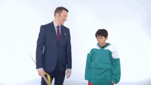 a man in a suit and tie is standing next to a young boy in a green jersey