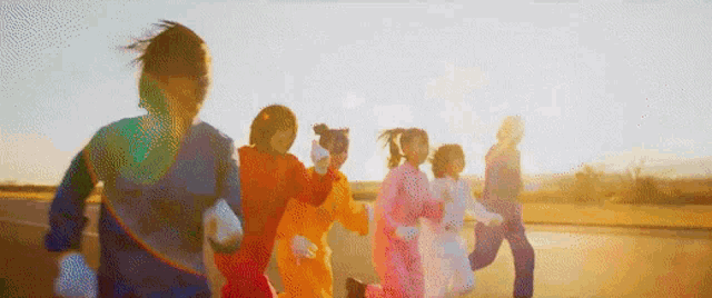 a group of children in colorful costumes are running down a street .