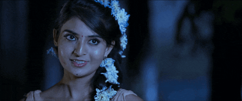 a woman with flowers in her hair is smiling and looking at the camera