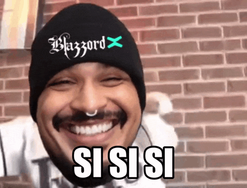 a man wearing a black beanie with the word blazzard on it smiles