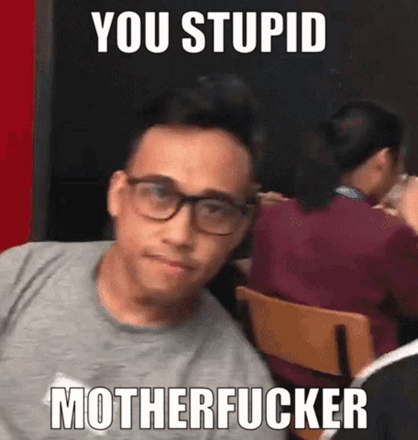 a man wearing glasses is sitting in a chair with the words you stupid motherfucker written above him