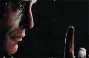 a close up of a man 's face with a finger pointing to his face .