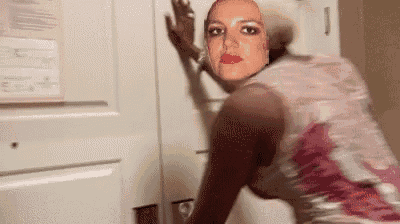 a woman with a picture of britney spears on her face is standing next to a door .