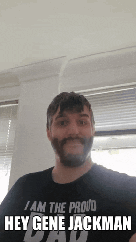 a man with a beard is wearing a black shirt that says i am the proud hey gene jackman
