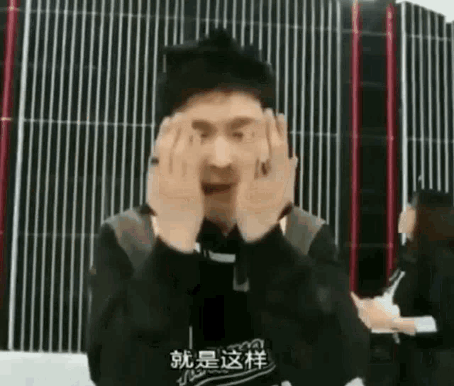 a man is covering his face with his hands in front of a wall .