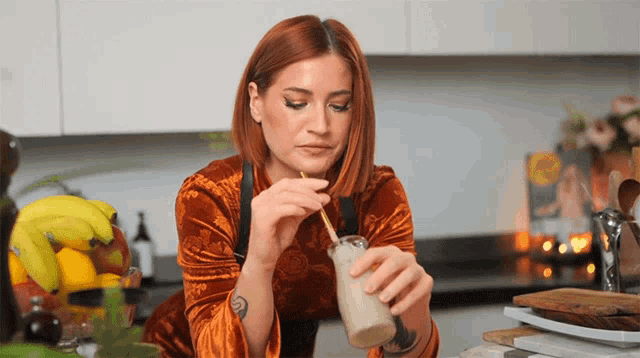 a woman with a tattoo on her arm is drinking a smoothie through a straw