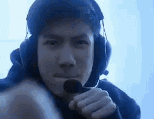 a man wearing headphones is holding a microphone in his mouth .