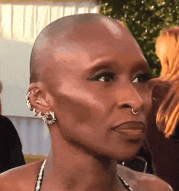 a close up of a woman 's face with a shaved head and earrings