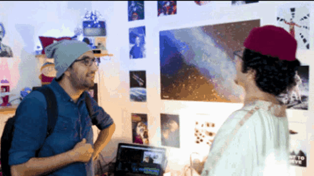 two men are standing in front of a wall with posters on it