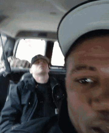 a man wearing a hat is taking a selfie with another man in a car