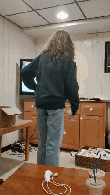 a woman in a green sweatshirt is dancing in a living room