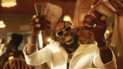 a man wearing sunglasses is holding a stack of money in his hands