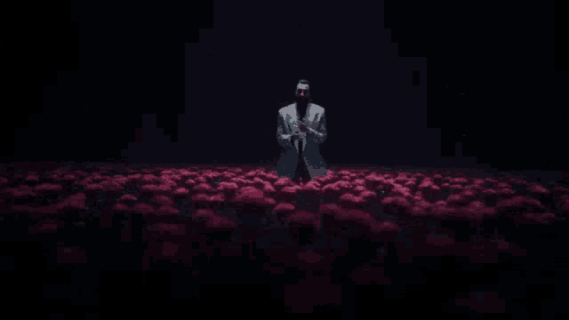 a man in a suit is standing in a field of red flowers in the dark .