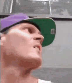 a man wearing a green hat and a purple hat is looking up .