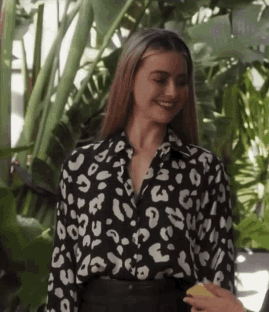 a woman in a black and white leopard print shirt smiles