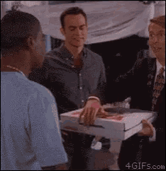 a man in a suit is holding a pizza box in his hand