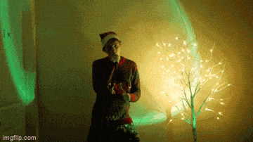a man in a santa hat is standing in front of a tree