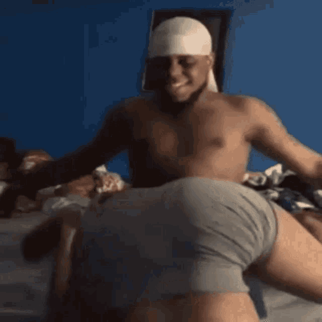 a shirtless man is sitting on top of another shirtless man in gray underwear .