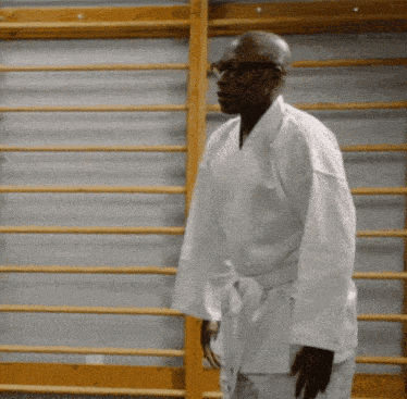 a man in a white karate uniform is standing in front of a wall