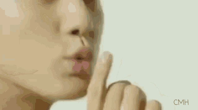 a woman is holding her finger to her mouth .