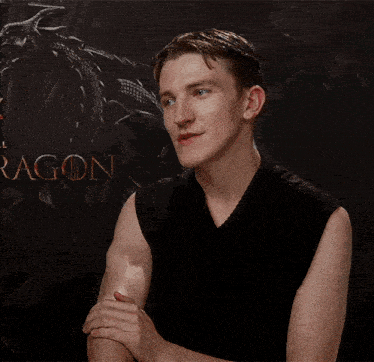 a man in a black shirt is clapping his hands in front of a dragon