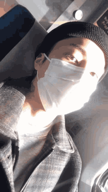 a man wearing a mask and a beanie looks at the camera