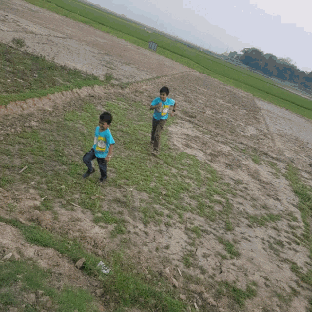 two young boys are standing next to a boat in a field