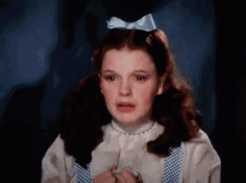 a close up of a girl with a blue bow in her hair crying .