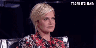 a woman with short blonde hair is sitting in a chair and making a funny face while wearing a leopard print shirt .