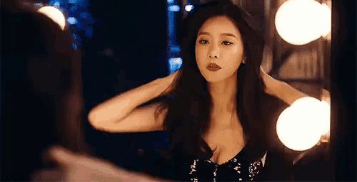 a woman is standing in front of a mirror adjusting her hair .