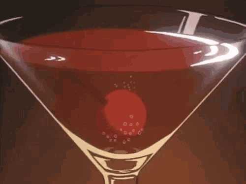 a martini glass with a cherry in it and bubbles coming out of it .