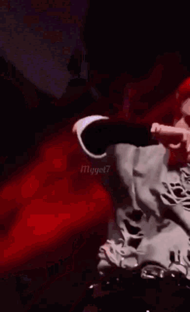 a man with red hair is wearing a white ripped sweater and giving the middle finger .
