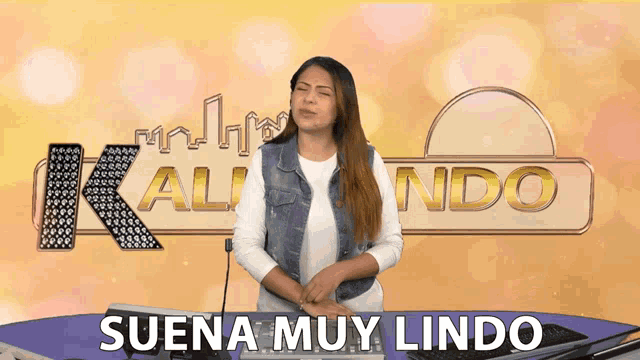 a woman stands in front of a sign that says kalindo suena muy lindo