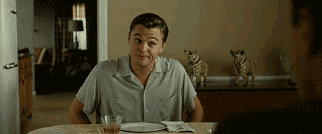a man is sitting at a table with a plate and a glass of whiskey