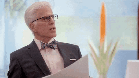 a man in a suit and bow tie is holding a piece of paper and looking at it .