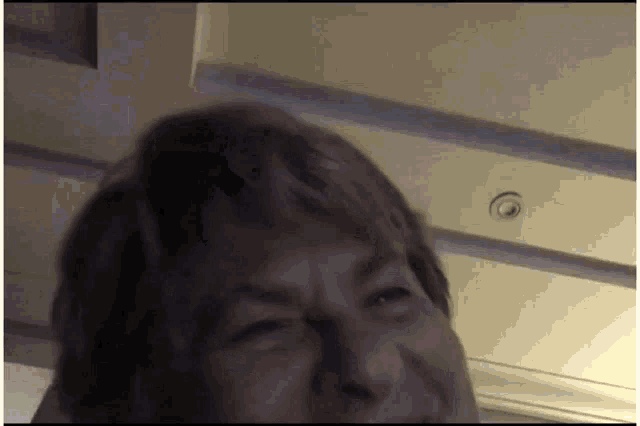 a close up of a person 's face with a ceiling light in the background
