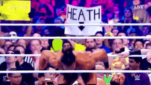 a wrestler is holding a sign that says heath