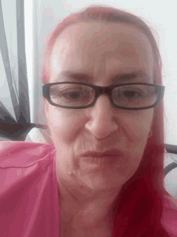 a woman wearing glasses and a pink shirt
