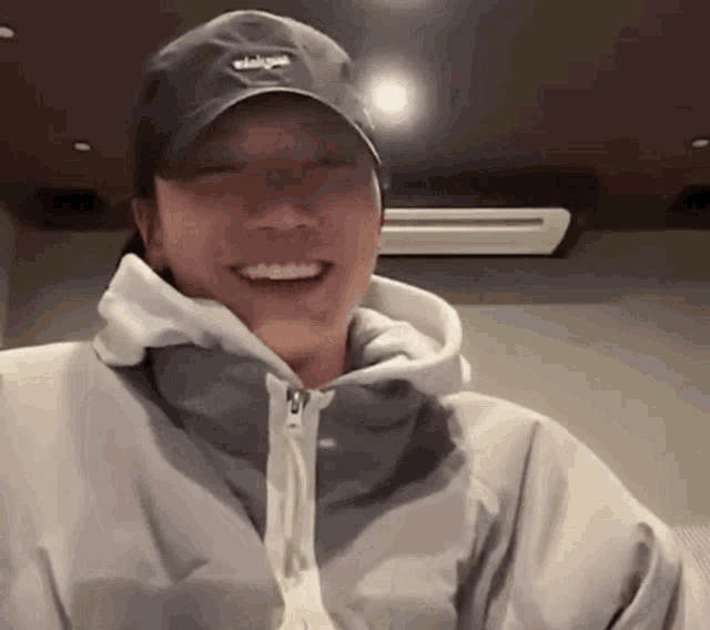 a man wearing a baseball cap and a hoodie is smiling .