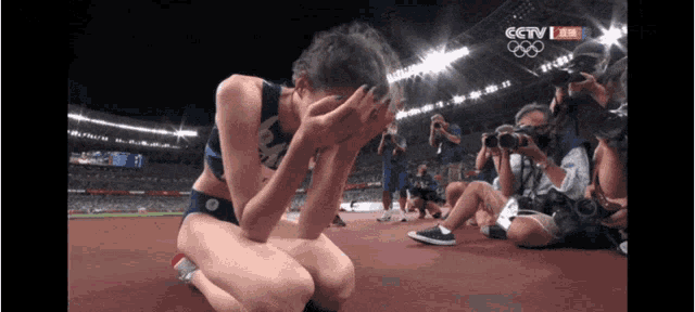 a woman is kneeling down in front of a crowd with cctv written on the bottom of the screen