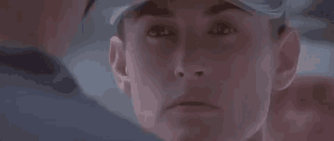 a close up of a woman 's face wearing a baseball cap and looking at a man .