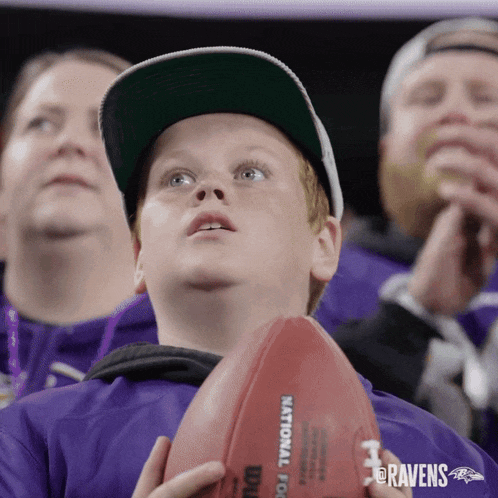 a young boy holds a football with the word national on it