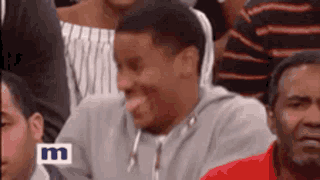 a man is sticking out his tongue while sitting in a crowd .