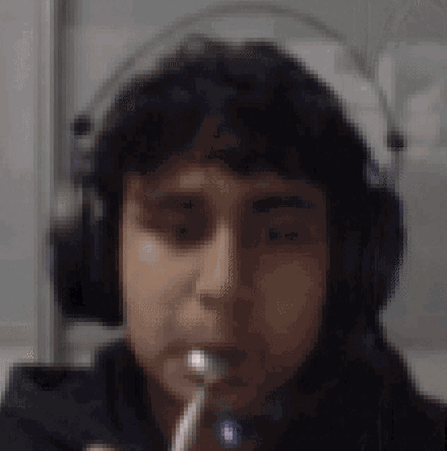 a blurry picture of a man wearing headphones and brushing his teeth .